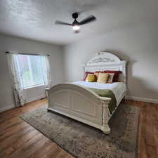 Bedroom with wood finished floors, ceiling fan, and a textured ceiling