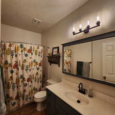 Bathroom featuring vanity, wood finished floors, a textured ceiling, and shower / bath combo with shower curtain