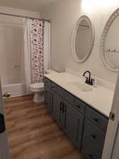 Full bathroom with vanity, wood finished floors, and shower / tub combo with curtain