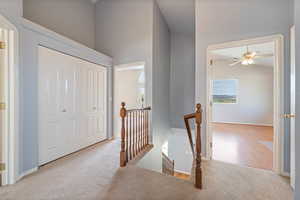 Hall featuring an upstairs landing, carpet, and high vaulted ceiling