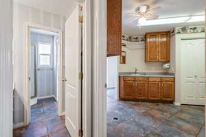 Kitchen featuring brown cabinets, light countertops, ceiling fan, and dark stone finish floors