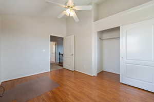 Unfurnished bedroom with wood finished floors, a closet, high vaulted ceiling, and a ceiling fan