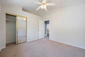 Unfurnished bedroom with carpet flooring, vaulted ceiling, a closet, and a ceiling fan