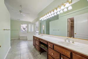 Full bath featuring a bath, lofted ceiling, double vanity, tile patterned floors, and ceiling fan