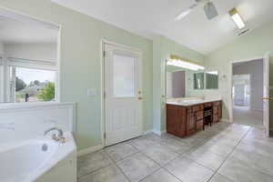Bathroom with double vanity, ceiling fan, a bath, vaulted ceiling, and tile patterned flooring