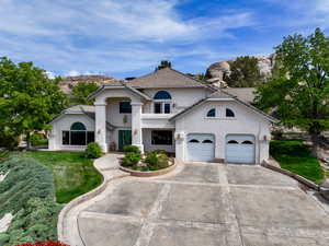 Mediterranean / spanish home featuring stucco siding, a front lawn, driveway, a garage, and a tiled roof