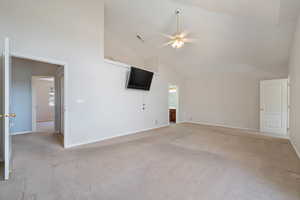 Unfurnished living room featuring high vaulted ceiling, light carpet, and a ceiling fan