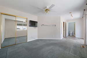 Carpeted empty room featuring a ceiling fan and baseboards