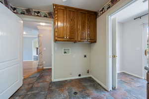 Laundry room featuring hookup for an electric dryer, hookup for a washing machine, gas dryer hookup, dark stone finish floors, and crown molding