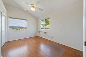 Spare room with lofted ceiling, wood finished floors, and ceiling fan