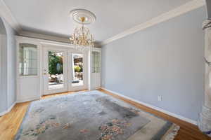 Unfurnished dining area featuring a chandelier, wood finished floors, crown molding, and a textured ceiling