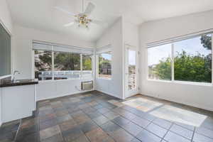 Unfurnished sunroom featuring healthy amount of natural light and vaulted ceiling