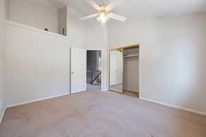 Unfurnished bedroom with carpet floors, a closet, high vaulted ceiling, and ceiling fan