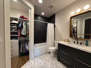 Full bathroom featuring vanity, shower / bath combination with curtain, a walk in closet, wood finished floors, and recessed lighting