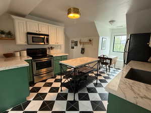 Kitchen featuring green cabinets, stainless steel appliances, white cabinets, and light countertops