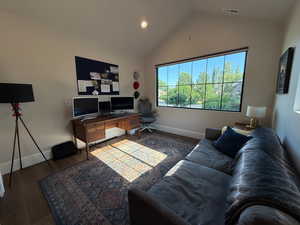 Living area with wood finished floors, vaulted ceiling, an office area, and recessed lighting