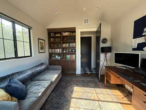 Living area with vaulted ceiling, wood finished floors, and an office area