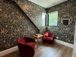 Sitting area at the top of the stairs featuring wood finished floors and wallpaper.