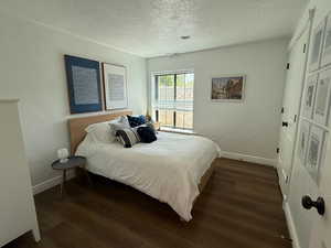 Bedroom with a textured ceiling and dark wood-style floors