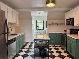 Kitchen featuring green cabinets, appliances with stainless steel finishes, white cabinetry, and light countertops