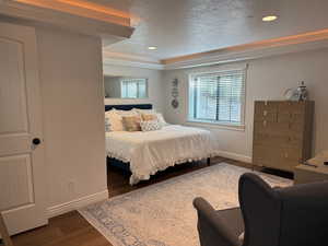 Bedroom featuring a textured ceiling, dark wood-style flooring, recessed lighting, and crown molding