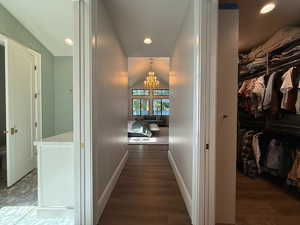 Corridor featuring a chandelier, wood finished floors, vaulted ceiling, and recessed lighting