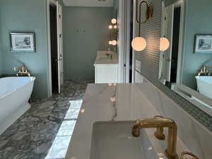 Primary bathroom with 2 vanities, vaulted ceiling, a freestanding bath, a shower stall, and marble flooring