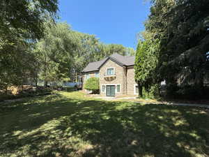 Side of house with stone siding and a sprawling yard and basement entrance