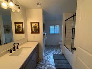 Full bathroom with tile patterned floors, vanity, combined bath / shower with glass door, and a textured ceiling