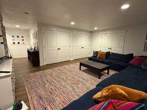 Living room with wood finished floors, recessed lighting.