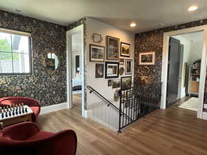 Sitting area at the top of the stairs featuring wood finished floors and wallpaper.