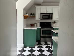 Kitchen with appliances with stainless steel finishes, light countertops, open shelves, white cabinetry, and green cabinets