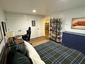 Bedroom with wood finished floors, a closet, and recessed lighting
