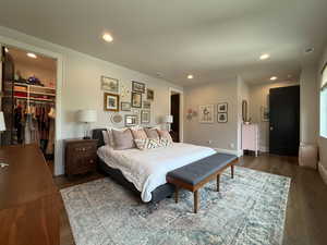 Bedroom with a spacious closet, dark wood finished floors, and recessed lighting