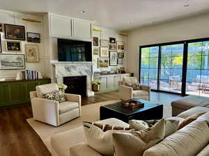 Living room with wood finished floors, a high end fireplace, and recessed lighting