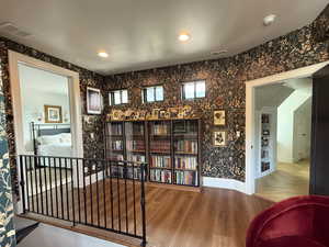 Sitting area at the top of the stairs featuring wood finished floors and wallpaper.