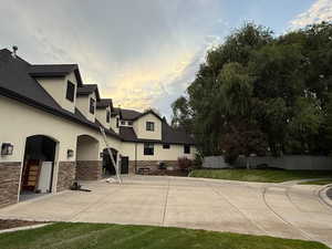 View of property exterior with stucco siding, stone siding, and parking area