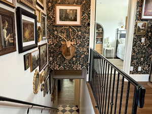 Staircase with wallpapered walls and wood finished floors