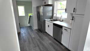 Kitchen featuring stainless steel appliances, dark wood-type flooring, white cabinetry, and light countertops