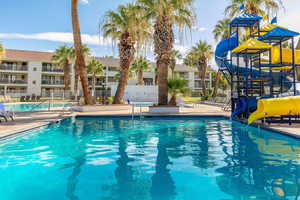 Community pool with a water slide and a patio