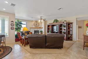Living room featuring a ceiling fan, a fireplace, recessed lighting, and light tile patterned floors