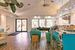 Living room with wood finished floors, plenty of natural light, vaulted ceiling, and a ceiling fan