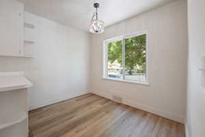 Unfurnished dining area with light wood finished floors and a chandelier