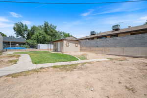 View of home's exterior with a fenced backyard and a storage shed