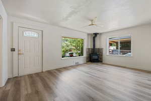 Foyer entrance featuring a wood stove, plenty of natural light, a ceiling fan, wood finished floors, and a textured ceiling