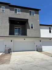 Rear view of house featuring stucco siding, an attached garage, and driveway