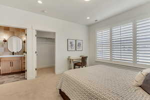 Bedroom featuring a spacious closet, recessed lighting, ensuite bathroom, and light carpet