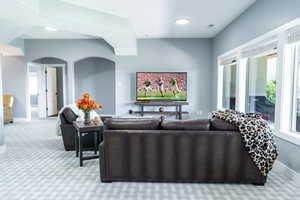 Carpeted living area featuring healthy amount of natural light and arched walkways