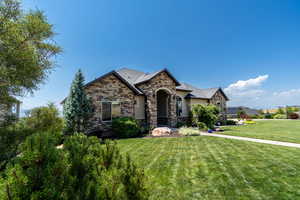 French provincial home with a front yard and stone siding