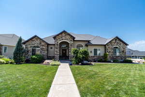 French provincial home with stone siding, stucco siding, and a front lawn